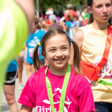 Girls on the Run smiles proudly wearing her 5K medal